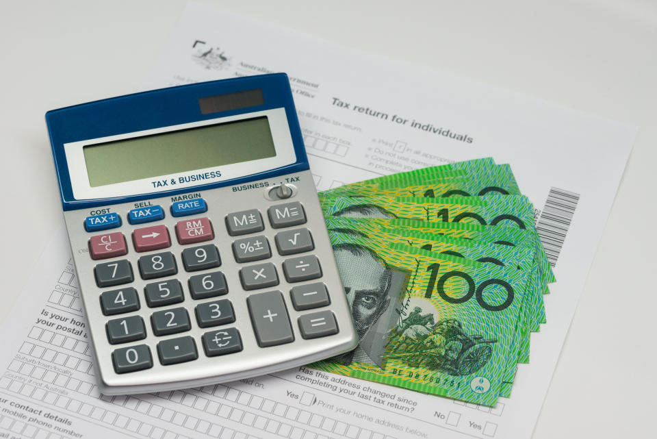 An image of a calculator, $100 bills and a tax return form.