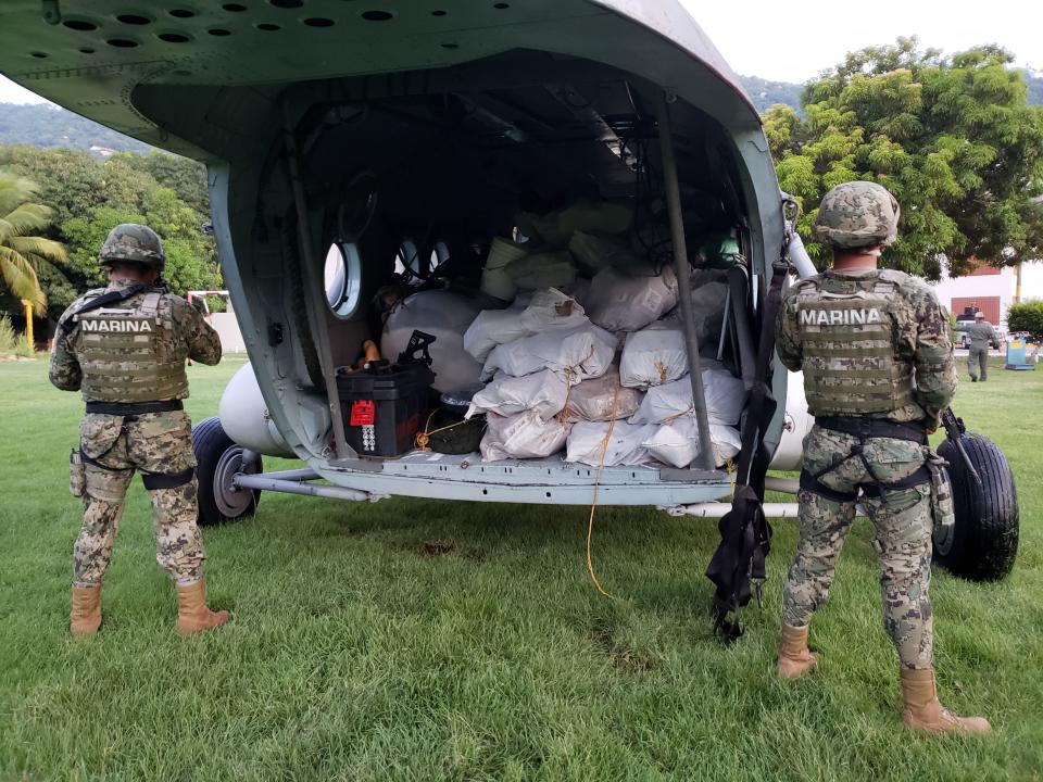 ADDS LOCATION - In this Thursday, Aug. 9, 2018 photo released by the Mexico's navy, soldiers stand guard around a military helicopter carrying packages of suspected cocaine, in Acapulco, Mexico. The Navy said in a statement Friday that it had seized nearly two tons of suspected cocaine off its southern Pacific coast. (Mexico Secretary of the Navy via AP)