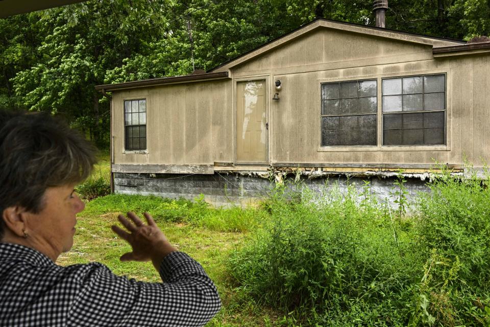 Pam Butler shows a reporter what she says is a black fungus that is growing on the trailer behind her house, during an interview on her property that borders a massive Jack Daniels barrelhouse complex, Wednesday, June 14, 2023, in Mulberry, Tenn. A destructive and unsightly black fungus which feeds on ethanol emitted by whiskey barrels has been found growing on property near the barrelhouses. (AP Photo/John Amis)