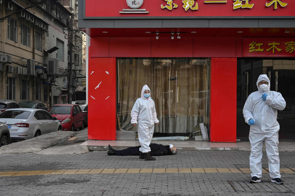 Image: Officials in protective suits checking on an elderly man wearing a facemask who collapsed and died on a street near a hospital in Wuhan (Hector Retamal / AFP - Getty Images file)