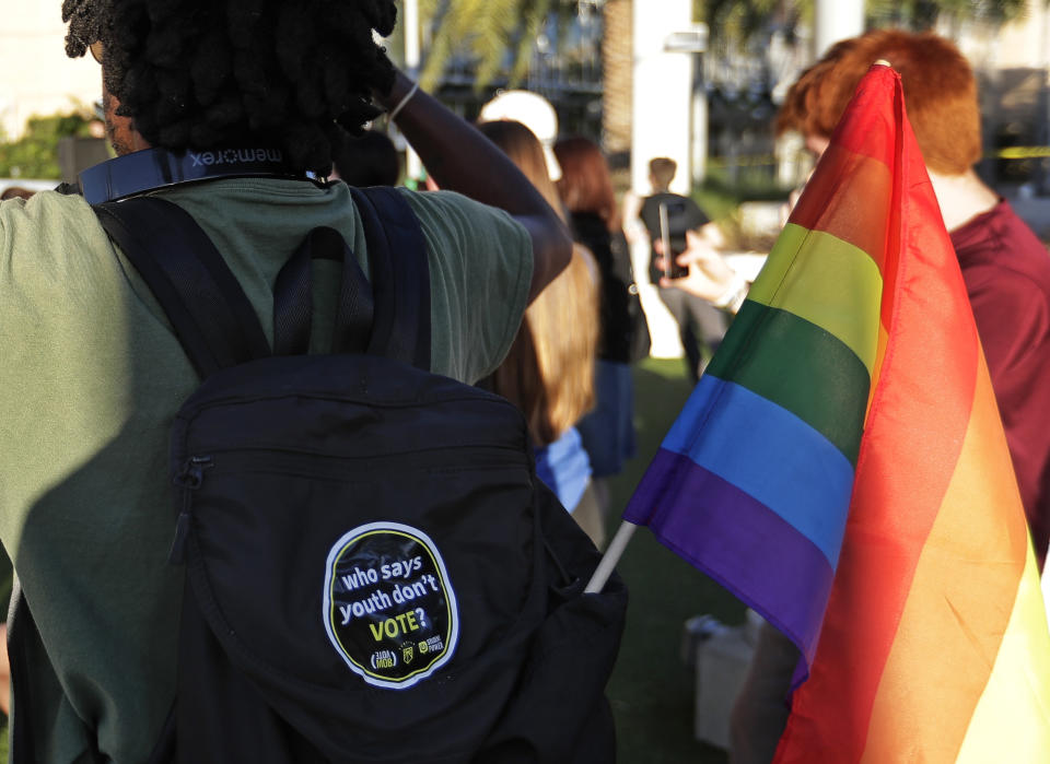 In this Wednesday, Oct. 31, 2018 photo, a student with a rainbow flag listens to speakers during a Vote for Our Lives rally at the University of Central Florida in Orlando, Fla. Nine months after 17 classmates and teachers were gunned down at their Florida school, Parkland students are finally facing the moment they’ve been leading up to with marches, school walkouts and voter-registration events throughout the country: their first Election Day. (AP Photo/John Raoux)