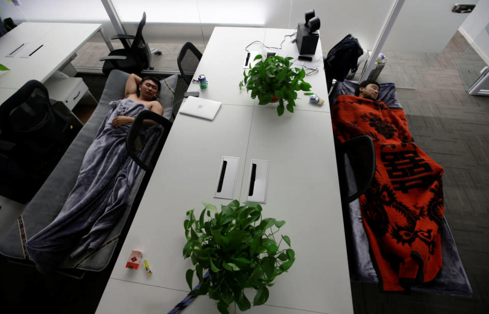Han Liqun, left, HR manager of RenRen Credit Management Co., and IT engineer Xiang Siyang sleep on camp beds at the office after finishing work early in the morning in Beijing on April 27, 2016. (Jason Lee/Reuters)