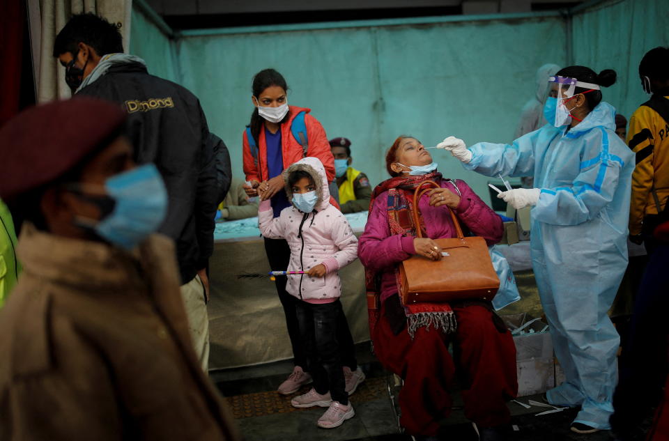 A healthcare worker collects a coronavirus disease (COVID-19) test swab sample from a woman amidst the spread of the disease, at a railway station in New Delhi, India, January 5, 2022. REUTERS/Adnan Abidi     TPX IMAGES OF THE DAY