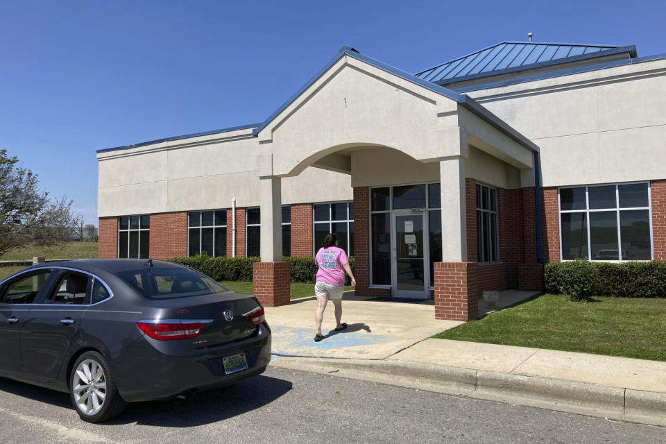 A woman walks into Family Medical Associates, which is encouraging patients to get COVID-19 vaccines, in Haleyville, Ala., Monday, April 5, 2021. The clinic is located in Winston County, which is trying to get more people immunized but is running into problems with both supply and willingness from a population that is both nearly all white and voted heavily for former President Donald Trump last year. (AP Photo/Jay Reeves)