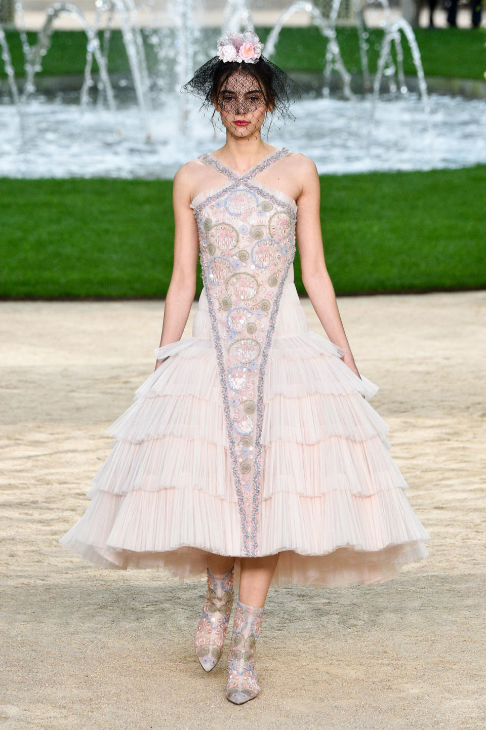 <p>Ein Model trägt bei der Chanel Frühjahr/Sommer 18 Haute Couture Modenschau ein hellrosa gestuftes Kleid mit farbigen Kristallverzierungen. (Bild: Getty Images </p>