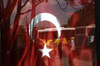 <p>People reflected on glass hold a Turkish flag at a bus station in Istanbul, July 25, 2016. Turkish media say authorities have issued warrants for the detention of 42 journalists and detained 31 academics, as the government pressed ahead with a crackdown against people with allegedly linked to a U.S.-based Muslim cleric. (Photo: Petros Karadjias/AP)</p>