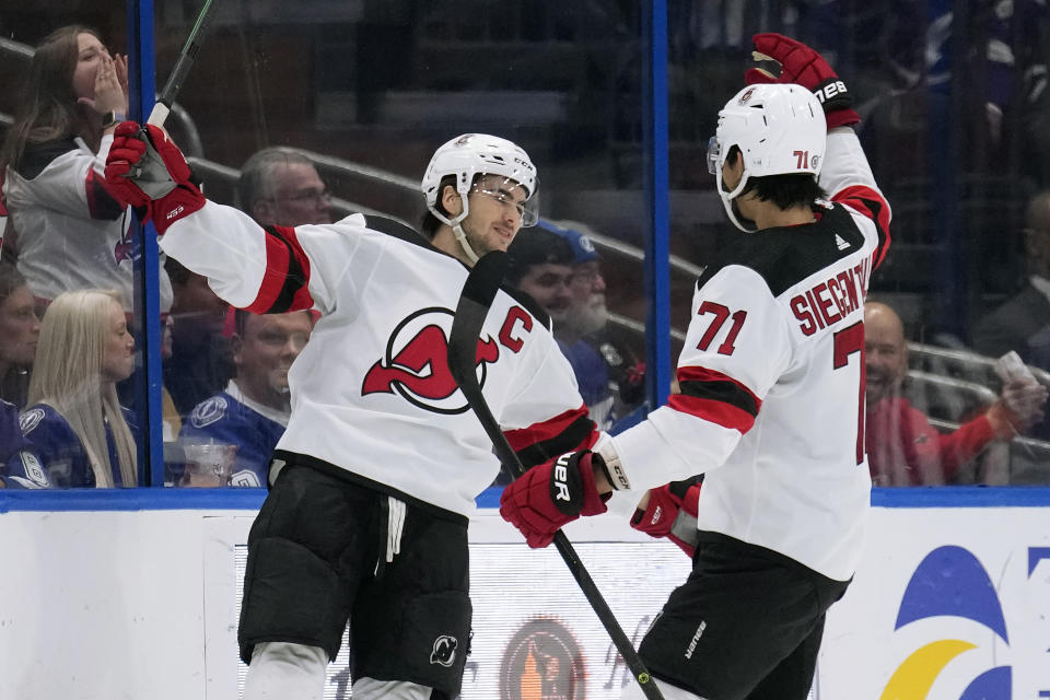 New Jersey Devils center Nico Hischier celebrates his goal against the Tampa Bay Lightning with defenseman Jonas Siegenthaler (71) during the.second period of an NHL hockey game Sunday, March 19, 2023, in Tampa, Fla. (AP Photo/Chris O'Meara)