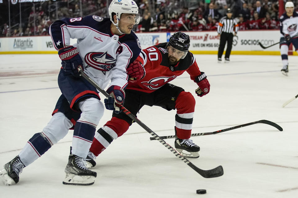Columbus Blue Jackets defenseman Zach Werenski (8) and New Jersey Devils left Wing Tomas Tatar (90) chase the puck during the second period of an NHL hockey game, Sunday, Oct. 30, 2022, in Newark, N.J. (AP Photo/Eduardo Munoz Alvarez)