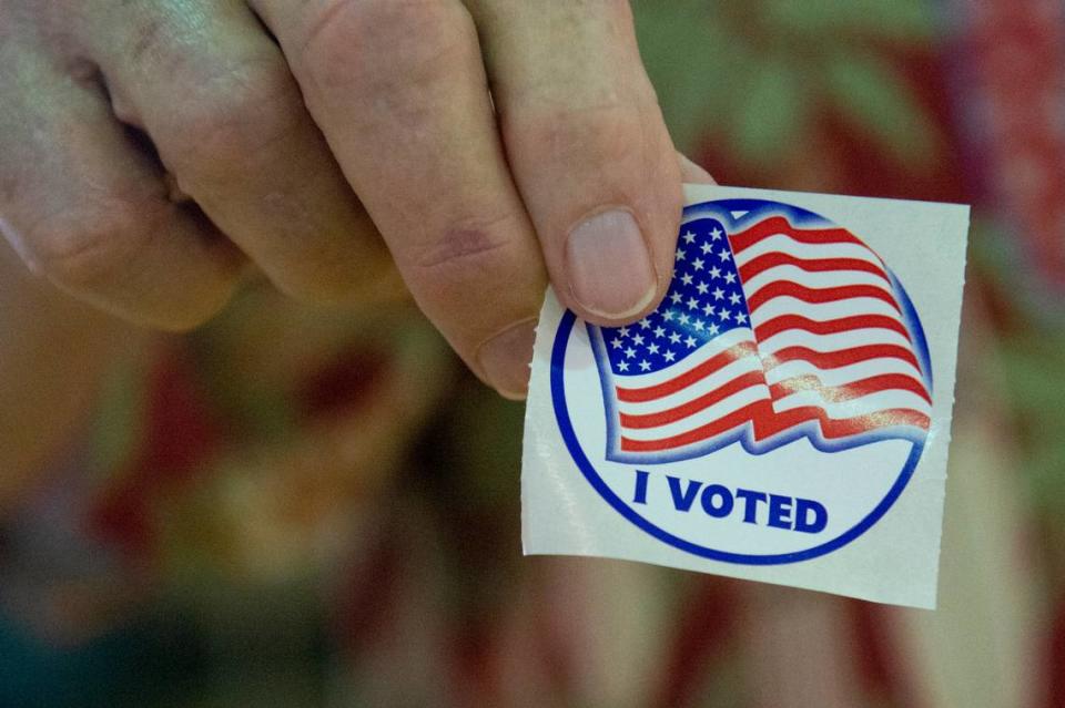 A poll worker holds up an election sticker at a polling location at Dr. Frank Gruich Sr. Community Center in Biloxi during the Mississippi Primary Election on Tuesday, Aug. 8, 2023.