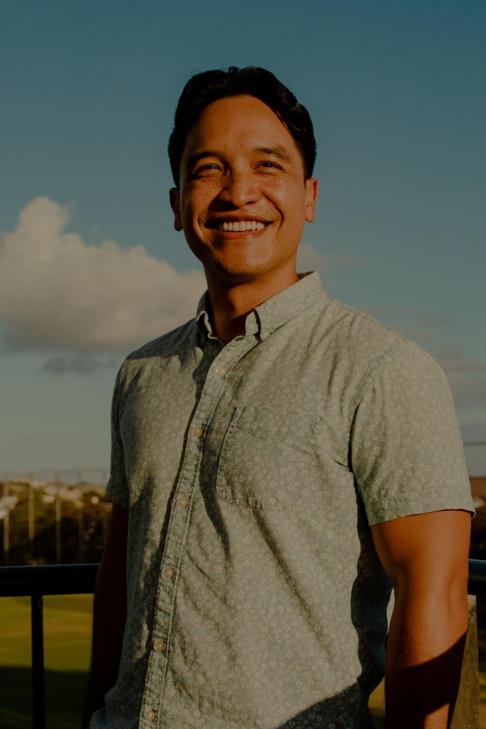 A man smiling in a blue collared shirt