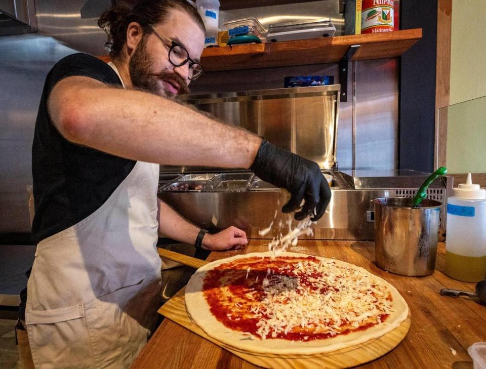 Pizza maker Doug Sorek sprinkles cheese on a pie at Far Out Pizza in Little Havana.