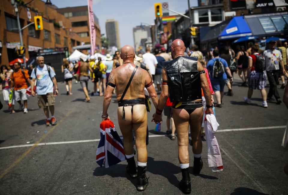 Two men walk hand in hand on Church Street before "WorldPride", a gay pride parade, in Toronto