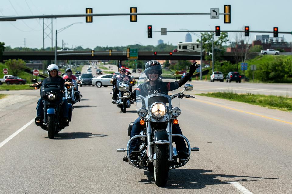 joni ernst waves as she rides a motorcycle with other bikers including mike pence down the highway