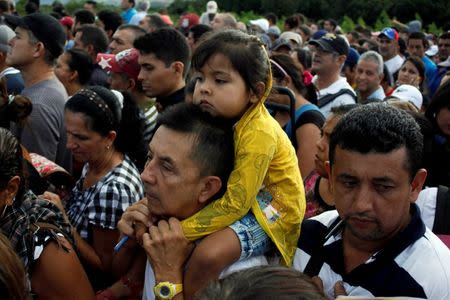 A man carries a child as people line up to cross over the Simon Bolivar international bridge to Colombia to take advantage of the temporary border opening in San Antonio del Tachira, Venezuela, July 17, 2016. REUTERS/Carlos Eduardo Ramirez