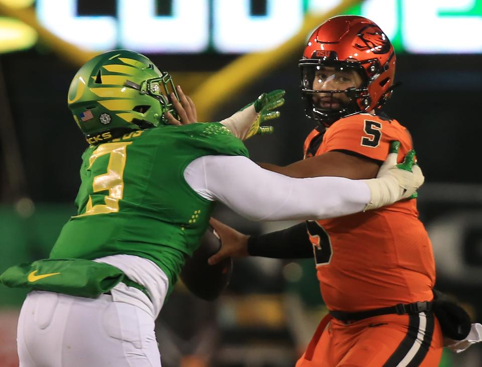 Oregon’s Brandon Dorlus, left, pressures Oregon State quarterback DJ Uiagalelei during the third quarter at Autzen Stadium Friday, Nov. 24, 2023.