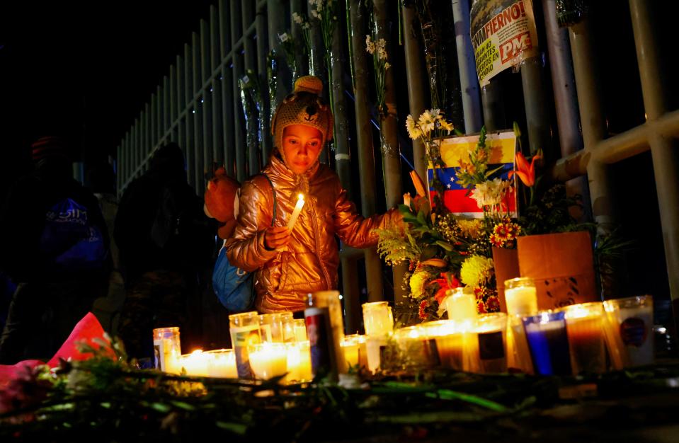 移民拘留中心外頭有小女孩點蠟燭為逝者緬懷。（路透社）