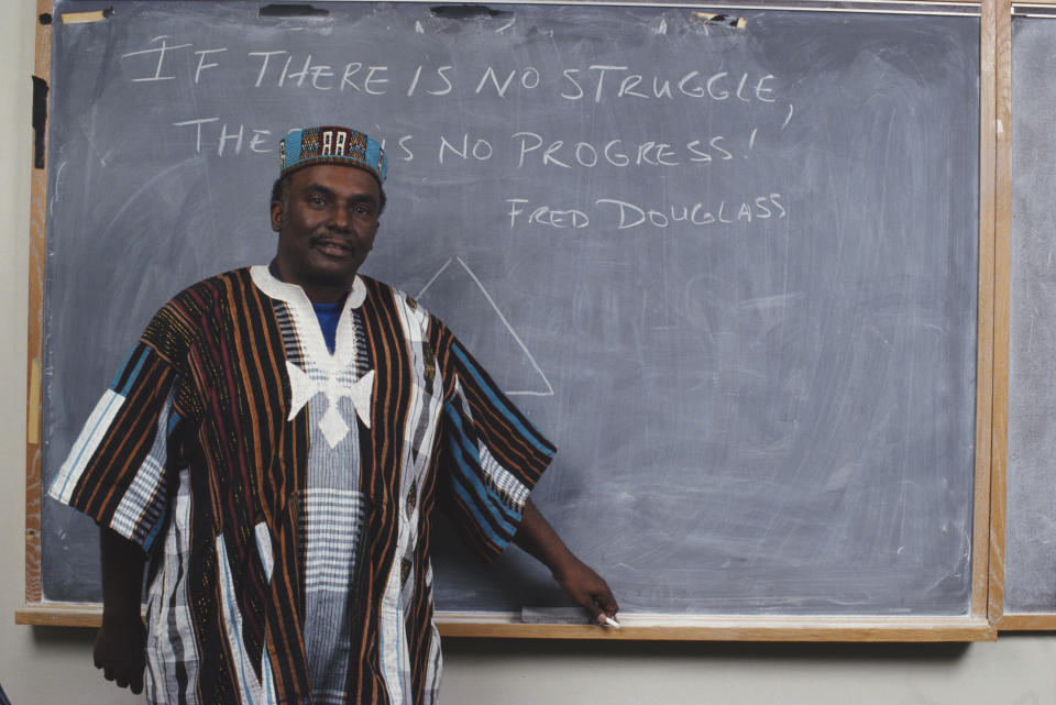 Leonard Jeffries Jr. in African dress at a blackboard carrying the message: If there is no struggle, there's is no progress — Fred Douglass.