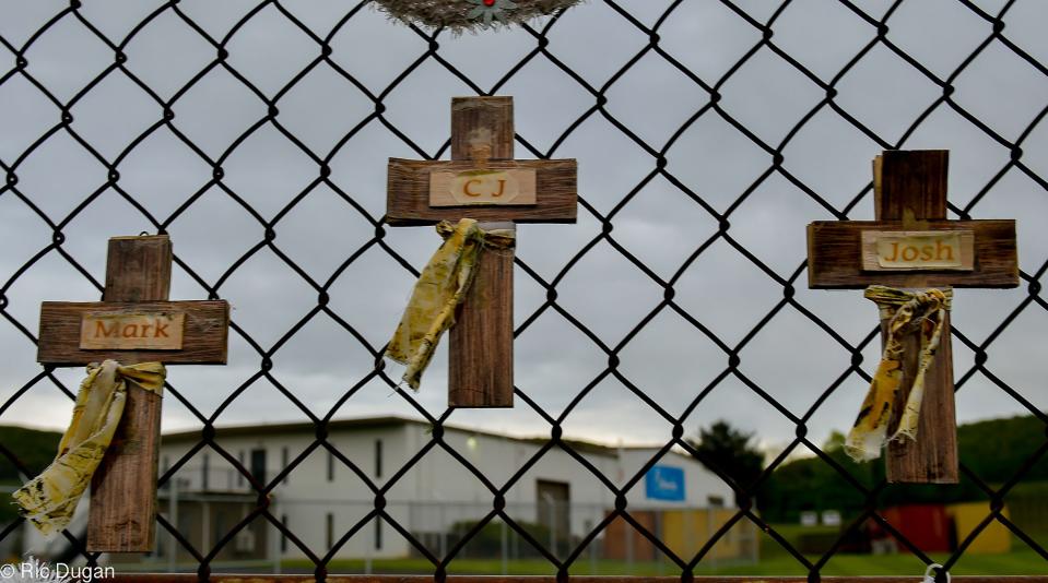 Crosses hang from a chain link fence outside the Columbia Machine, Inc. building where there workers were killed in a mass shooting in June of 2022.