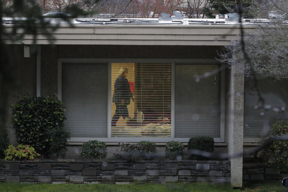 A nurse wearing a mask walks past the room of Chuck Sedlacek — who has tested positive for the COVID-19 coronavirus — Friday, March 13, 2020, as seen through the window of his room at Life Care Center in Kirkland, Wash., near Seattle. The facility has been at the center of the coronavirus outbreak in the state, and Sedlacek's son Scott Sedlacek said that he and his siblings have barely spoken to their father inside the center, who in addition to testing positive for the coronavirus, has blindness, neuropathy, and has difficulty using a phone, saying he is more of an "inmate" than a patient. Residents of assisted living facilities and their loved ones are facing a grim situation as the coronavirus spreads across the country, placing elderly people especially at risk. (AP Photo/Ted S. Warren)