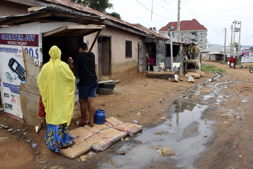 Two women buy mobile phone cards from a stall close to sewage water in Abuja, Nigeria, Friday, Sept. 3, 2021. Nigeria is seeing one of its worst cholera outbreaks in years, with more than 2,300 people dying from suspected cases as the West African nation struggles to deal with multiple disease outbreaks. This year’s outbreak which is associated with a higher case fatality rate than the previous four years is also worsened by what many consider to be a bigger priority for state governments: the COVID-19 pandemic. (AP Photo/Gbemiga Olamikan)