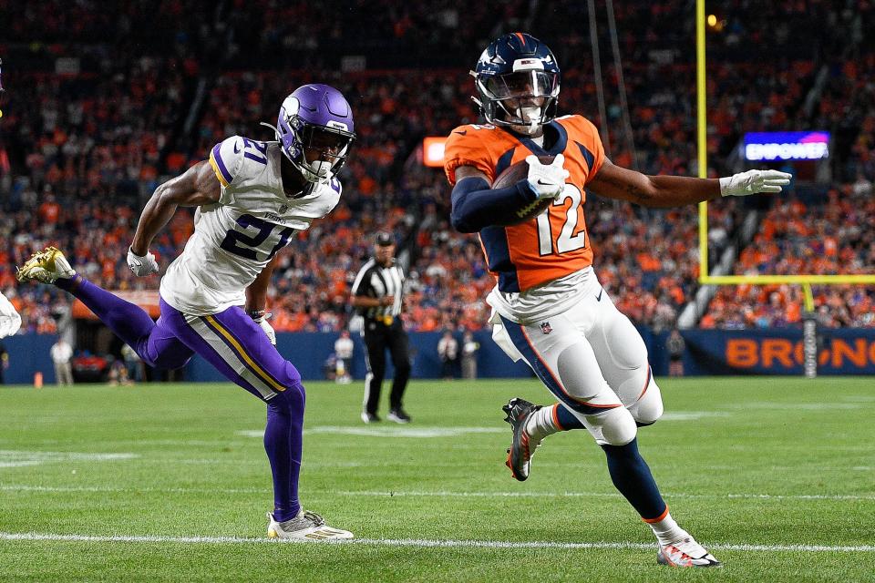 Denver Broncos WR Montrell Washington (12) carries the ball for a touchdown under coverage by Minnesota Vikings CB Akayleb Evans (21) at Empower Field at Mile High on August 27, 2022 in Denver, Colorado.