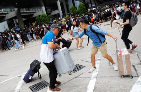 People and protesters run away from the riot police outside the terminals at Hong Kong International Airport, in Hong Kong