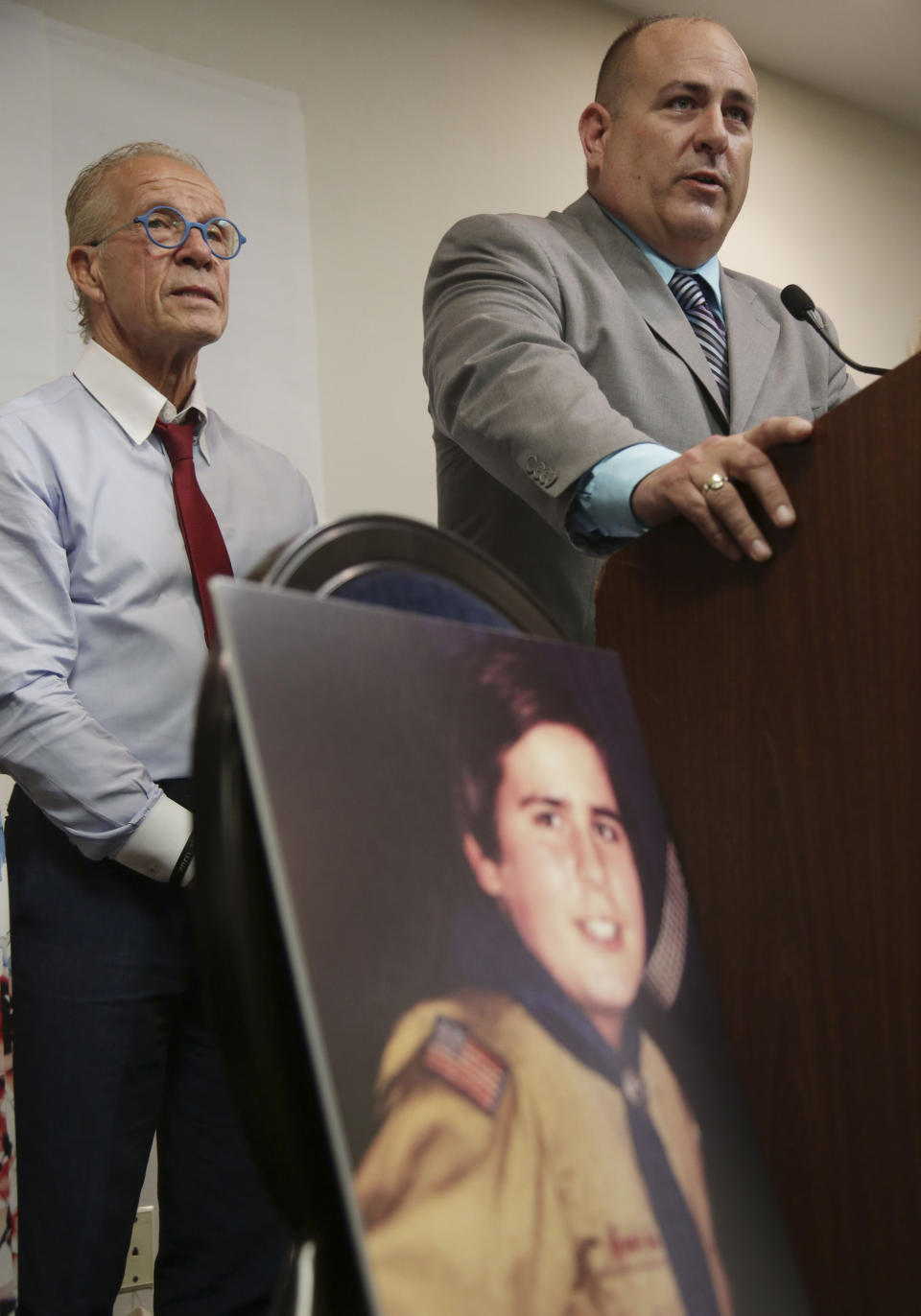 A picture of Richard Halvorson as a boy scout in 1982, when he was 11-years-old, is displayed while Halvorson, right, and attorney Jeff Anderson speak during a news conference in Newark, N.J., Tuesday, April 30, 2019. Halvorson is alleging sexual abuse in a lawsuit filed against the Boy Scouts of America. (AP Photo/Seth Wenig)