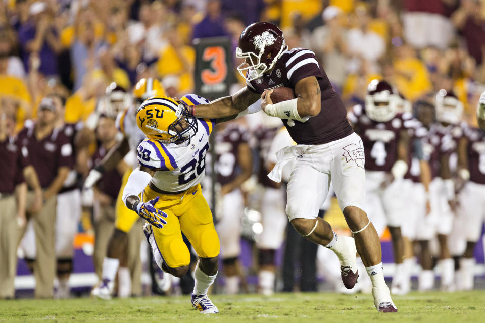 BATON ROUGE, LA - SEPTEMBER 20: Dak Prescott #15 of the Mississippi State Bulldogs stiff arms Jalen Mills #28 of the LSU Tigers at Tiger Stadium on September 20, 2014 in Baton Rouge, Louisiana.  The Bulldogs defeated the Tigers 34-29.  (Photo by Wesley Hitt/Getty Images)