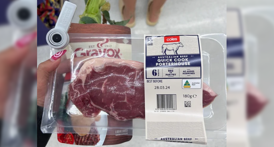 The Melbourne shopper holds up the steak meat taking a picture of the security tags at Coles. 