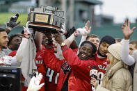 Louisville head coach Deion Branch holds up the trophy as his players celebrate around him after their 24-7 win over Cincinnati in the Fenway Bowl NCAA college football game at Fenway Park Saturday, Dec. 17, 2022, in Boston. (AP Photo/Winslow Townson)