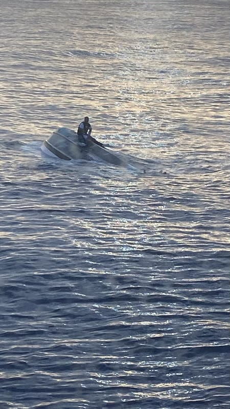 Man sits on a capsized boat off the coast of Florida