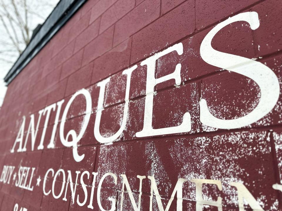 painted antique store sign with light dusting of snow on building exterior