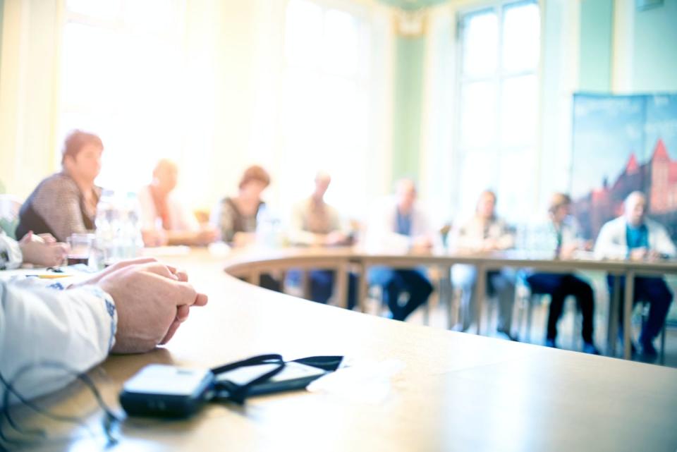 A picture of people sitting around a desk.