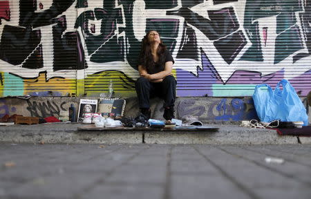 A street vendor reacts as she sits behind used items for sale in central Athens, Greece, July 7, 2015. REUTERS/Christian Hartmann