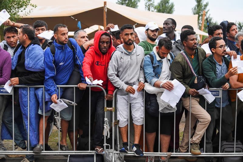 Refugees wait outdoors on the damp ground at the main reception centre for asylum seekers, in Ter Apel