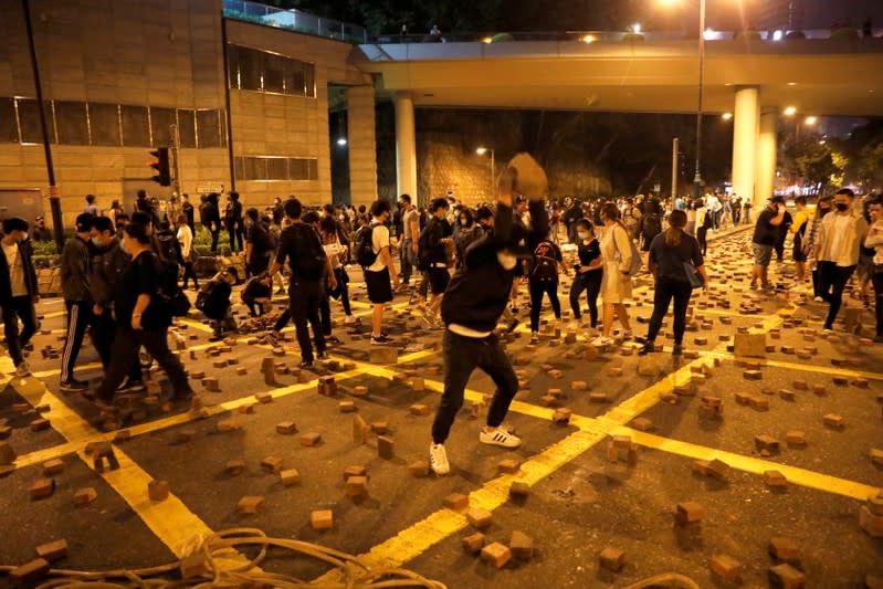 An anti-government demonstrator throws a stone as they block a road near the Hong Kong Polytechnic University (PolyU) in Hong Kong