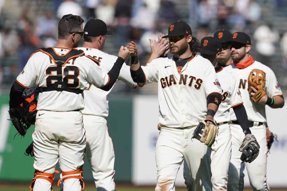 San Francisco Giants catcher Buster Posey (28) celebrates with shortstop Brandon Crawford, center right, and teammates after they defeated the Colorado Rockies in a baseball game in San Francisco, Saturday, April 10, 2021. (AP Photo/Jeff Chiu)