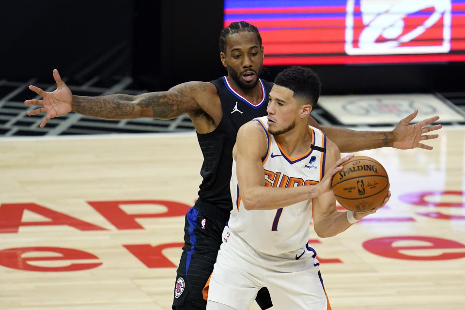 Phoenix Suns guard Devin Booker (1) holds the ball as Los Angeles Clippers forward Kawhi Leonard defends during the first half of an NBA basketball game Thursday, April 8, 2021, in Los Angeles. (AP Photo/Marcio Jose Sanchez)