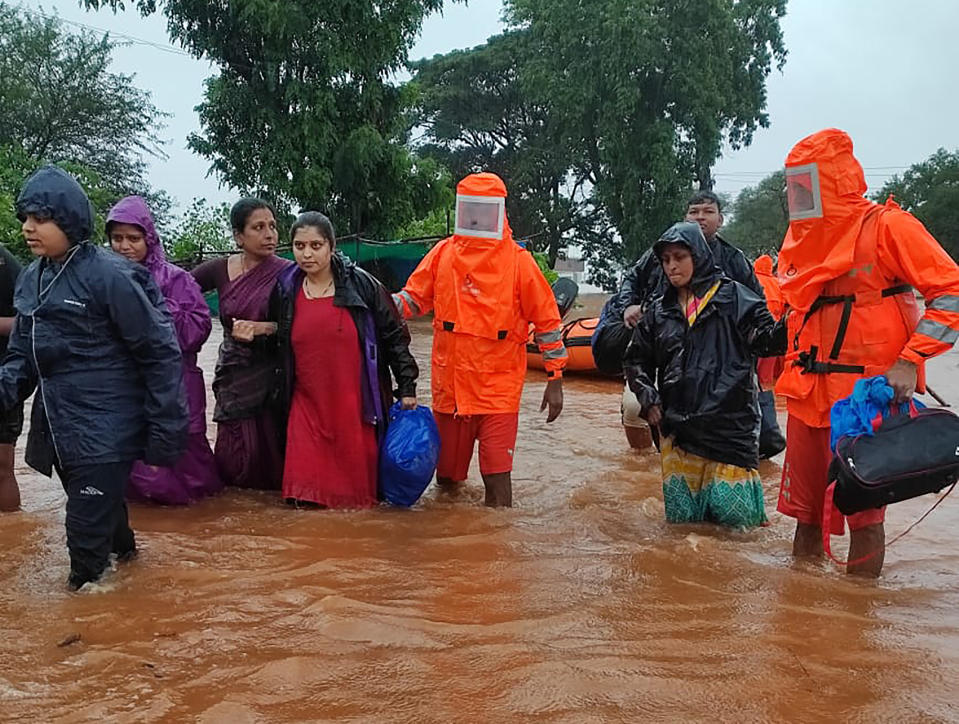 This photograph provided by India's National Disaster Response Force (NDRF) shows NDRF personnel rescuing people stranded in floodwaters in Chikhali, in the western Indian state of Maharashtra, Friday, July 23, 2021. Landslides triggered by heavy monsoon rains hit parts of western India, killing more than 30 people and leading to the overnight rescue of more than 1,000 other people trapped by floodwaters, officials said Friday.(National Disaster Response Force via AP)