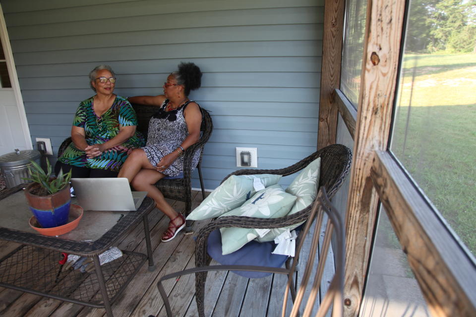 Ruby Penn, left, and her sister, Penny Blue, sit on the porch of their Franklin County, Va., home on Monday, July 6, 2020. Ruby Penn, who frequently drives past a Confederate flag flying on private property near her home, said living in Franklin County means living under constant symbols of racism that still exist there. (AP Photo/Sarah Blake Morgan)