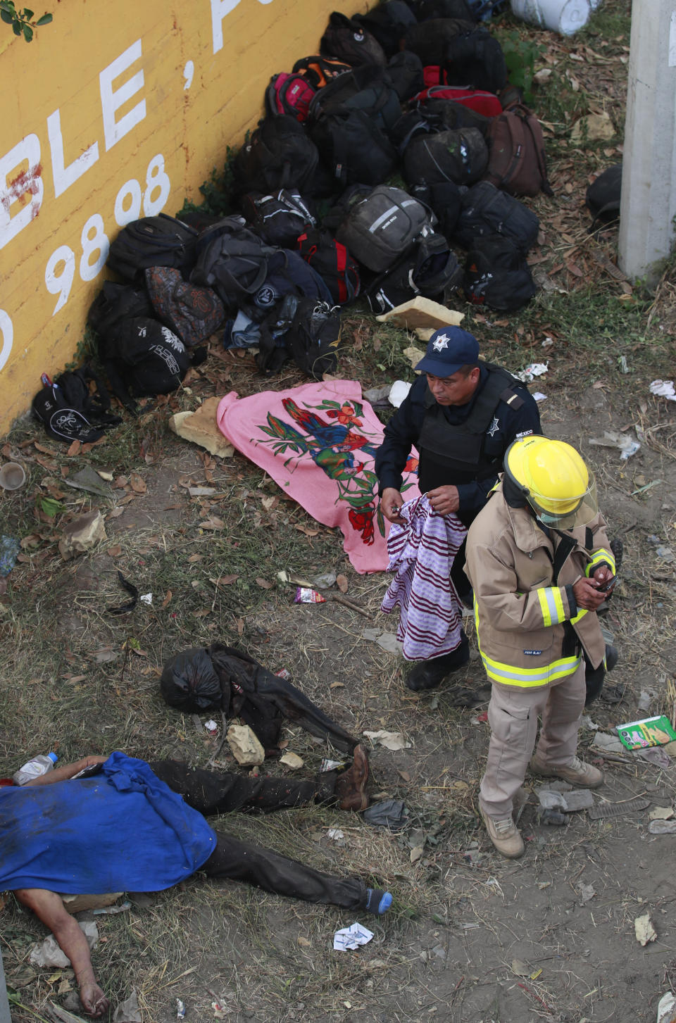 The body of a man lies on the side of the road next to the overturned truck on which he was traveling near Tuxtla Gutierrez, Chiapas state, Mexico, Thursday, Dec. 9, 2021. Mexican authorities say at least 49 people were killed and dozens more injured when the truck carrying the migrants rolled over on the highway in southern Mexico. (AP Photo)