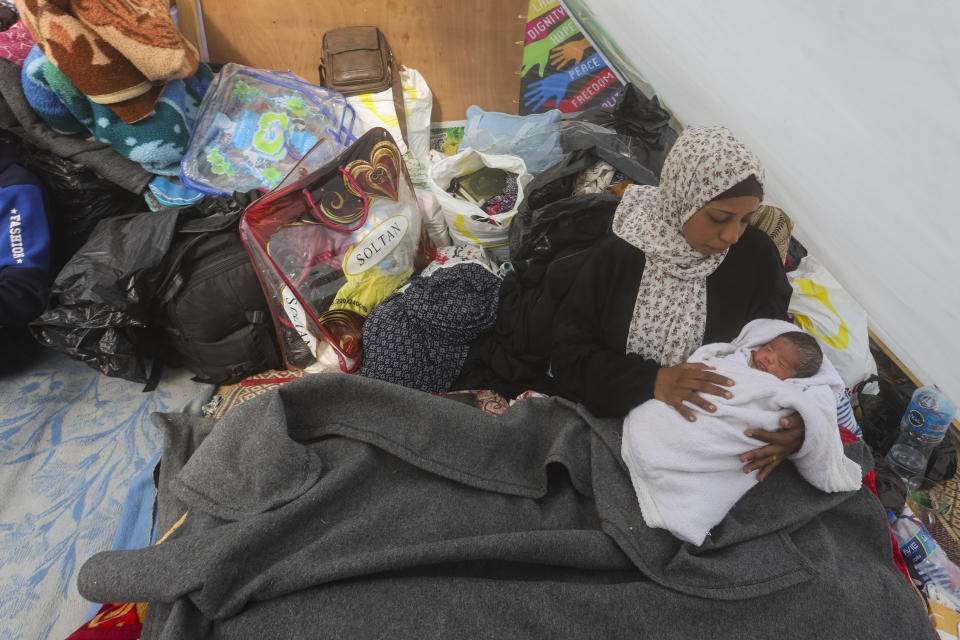 FILE - A Palestinian woman displaced by Israeli air and ground offensive on the Gaza Strip holds her baby in a tent near Kerem Shalom crossing in Rafah on Jan. 14, 2024. The war in Gaza has sparked a humanitarian catastrophe that has prompted shortages of the most basic necessities. Among those hardest hit are babies, young children and their parents. That's because diapers and formula are hard to find or have prices that are increased to unaffordable prices. Parents are looking to inadequate or even unsafe alternatives. (AP Photo/Hatem Ali)