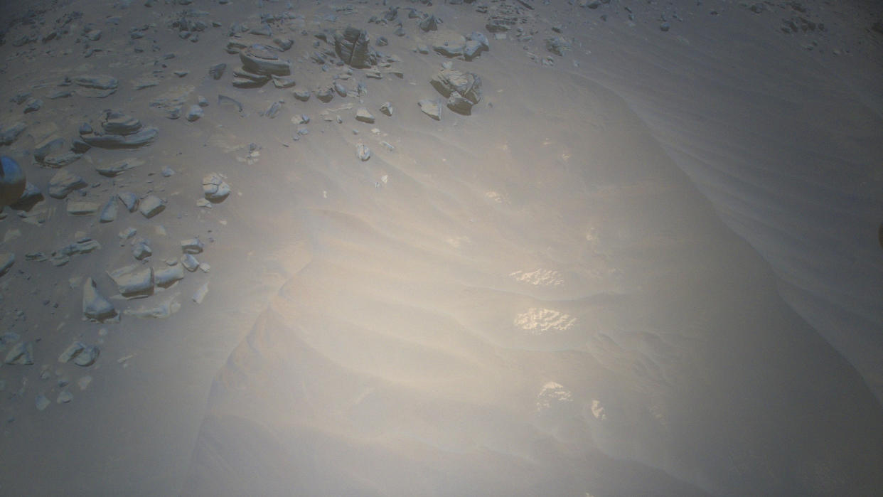  A photo looking down at a sandy patch of martian ground, with boulders strewn near the top of the frame. 