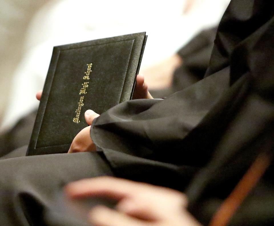 A graduate holds his diploma Sunday, June 5, 2022, during commencement at Canton Memorial Civic Center.