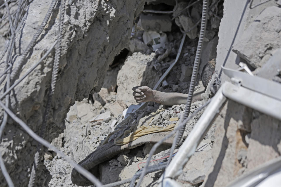 An arm protrudes from the rubble of a Houthi detention center destroyed by Saudi-led airstrikes, that killed at least 60 people and wounding several dozen according to officials and the rebels' health ministry, in Dhamar province, southwestern Yemen, Sunday, Sept. 1, 2019. The officials said the airstrikes took place Sunday and targeted a college in the city of Dhamar, which the Houthi rebels use as a detention center. The Saudi-led coalition said it had hit a Houthi military facility used as storages for drones and missiles in Dhamar. (AP Photo/Hani Mohammed)