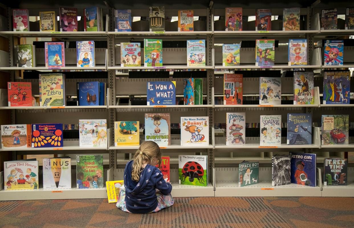 Ayla Richards, who is visiting her grandparents from Toronto, reads a book in the children's area of the Lakes Regional Library on Friday, Feb. 28, 2020, in Fort Myers.