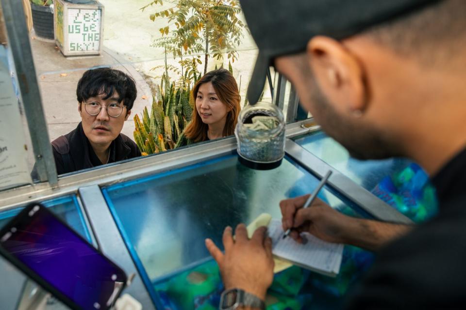 Customers peruse the menu at Simón mariscos truck on Thursday, Dec. 29, 2022 in Los Angeles.