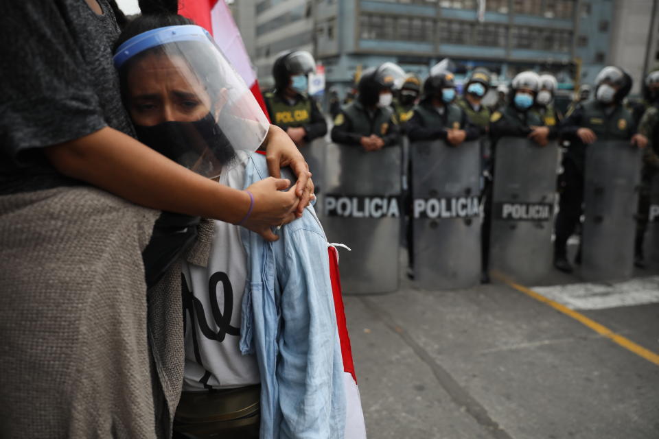 Alejandra Rodriguez is embraced by her sister Luciana as police block them and other supporters of former President Martin Vizcarra from reaching Congress where lawmakers voted the previous night to remove Vizcarra from office in Lima, Peru, Tuesday, Nov. 10, 2020. Congress voted to oust Vizcarra over his handling of the new coronavirus pandemic and unproven allegations of corruption years ago. (AP Photo/Rodrigo Abd)