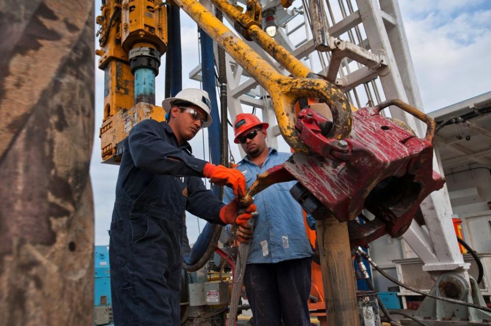 Driller Adrian Vallarta, left, and floor hand Jose Garza attach a drill screen to the elevator on Orion Drilling Co.'s Perseus drilling rig near Encinal in Webb County, Texas, U.S., on Monday, March 26, 2012. The Perseus is drilling for oil and gas in the Eagle Ford Shale, a sedimentary rock formation underlying an area of South and East Texas. Photographer: Eddie Seal/Bloomberg via Getty Images