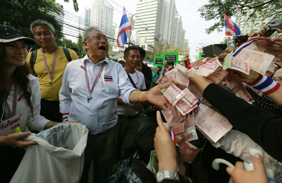 Supporters hand money to Thai anti-government protest leader Suthep Thaugsuban during a march Thursday, Jan. 23, 2014, in Bangkok, Thailand. As a state of emergency came into effect Wednesday in the Thai capital, defiant protesters marched on government offices and defaced the wall outside of national police headquarters, while a prominent government supporter in the country's northeast was the target of a shooting attack. (AP Photo/Wason Wanichakorn)